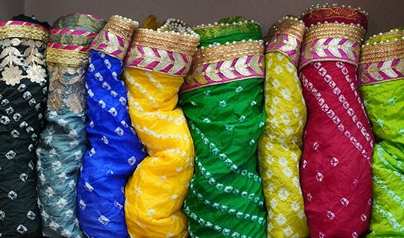 Traditional Rajasthan dress materials is neatly stacked for sale in a cloth merchant shop in India. Colorful fabric street stall. Bandhej or Bandhani widely used in Rajasthan FM4