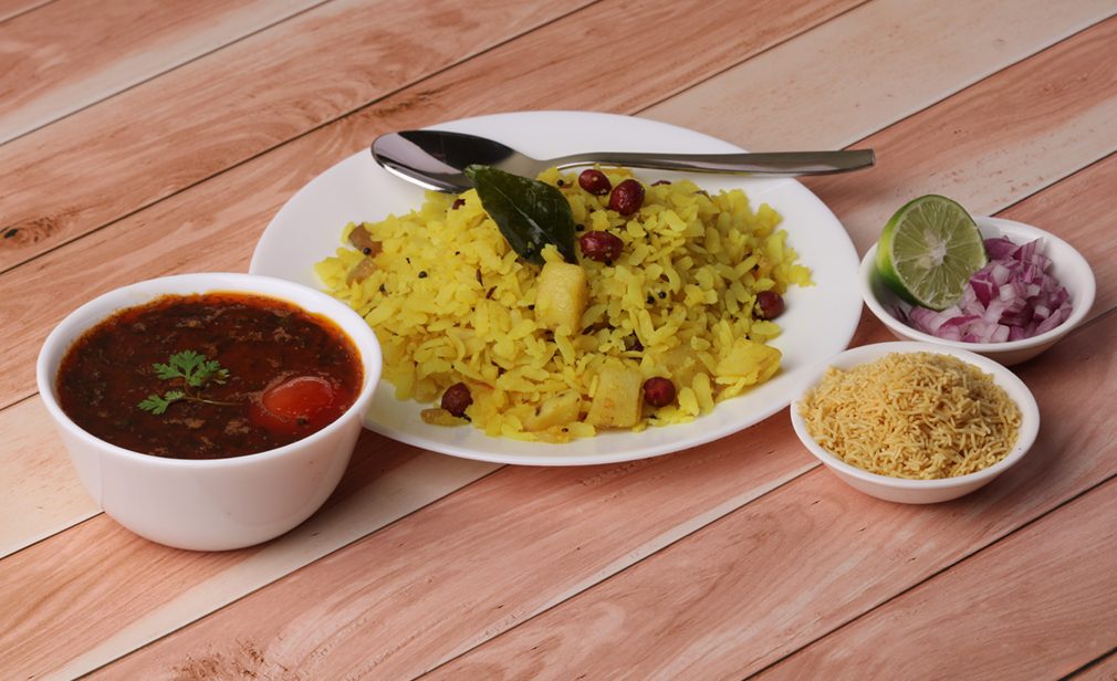 Aloo/Kanda Poha or Tarri Pohe with spicy chana masala/curry. Served in ceramic plate.