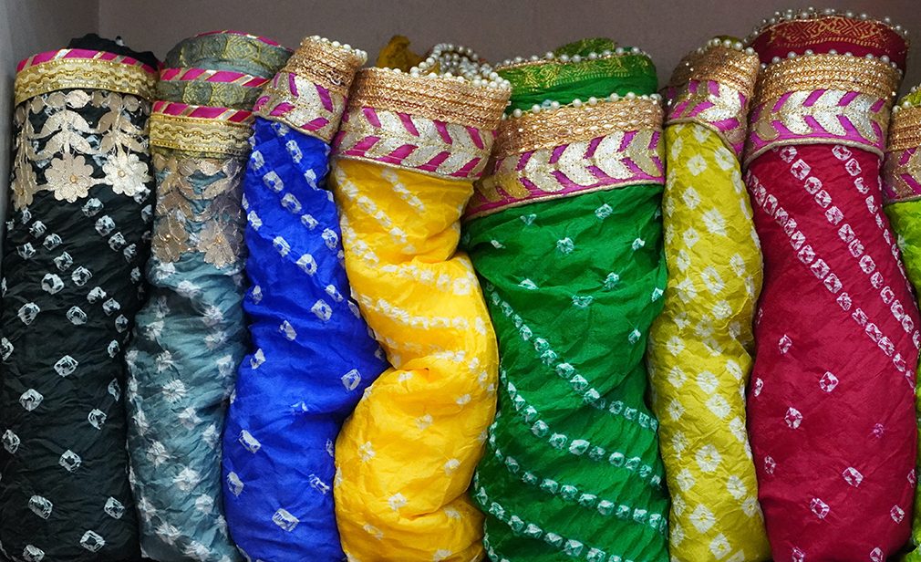 Traditional Rajasthan dress materials is neatly stacked for sale in a cloth merchant shop in India. Colorful fabric street stall. Bandhej or Bandhani widely used in Rajasthan FM4