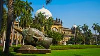 Buddha head carvings on the green grass of the museum. The Prince of Wales Museum (Chhatrapati Shivaji) is located in Mumbai, Maharashtra, India.