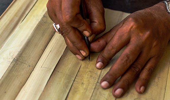 Hands of  Artist drawing  Story telling Artwork on Palm leaf at Raghurajpur Village, Orissa. Selective focus is used.