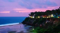 Kerala, India. Varkala beach at night, various cafes and restaurants at the cliff with colorful sunset sky and motion blurred Laccadive Sea and Papanasam beach in Kerala, India
