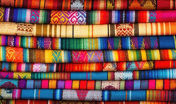 Andes textile fabric pile on Cusco handicraft market, Peru.