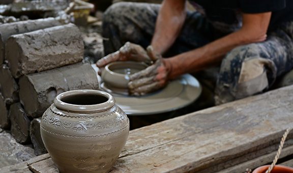 traditional pottery making with background of potter's hands shaping a bowl on the spinning by clay, mold, crockery, earthenware, terracotta pot