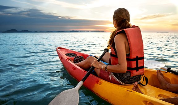 Couple kayaking together. Beautiful young couple kayaking on lake together and smiling at sunset