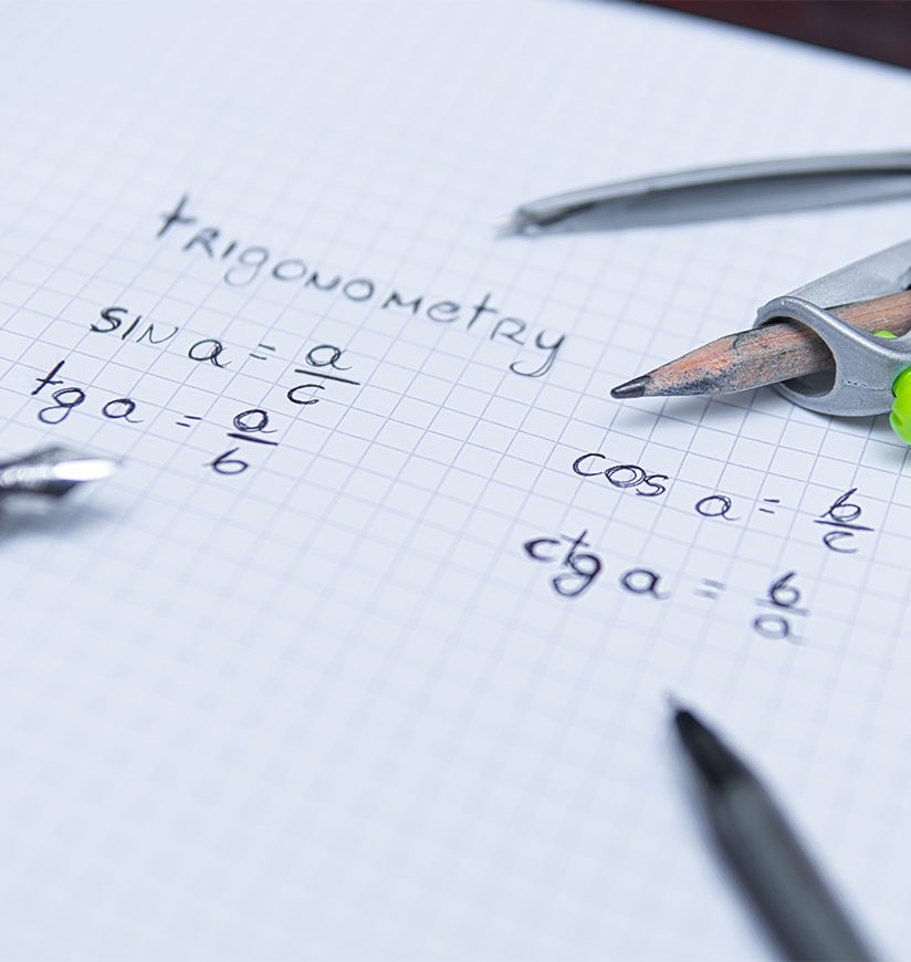 close-up on trigonometric formulas next to pen and compass. Mathematical formulas and problem solving