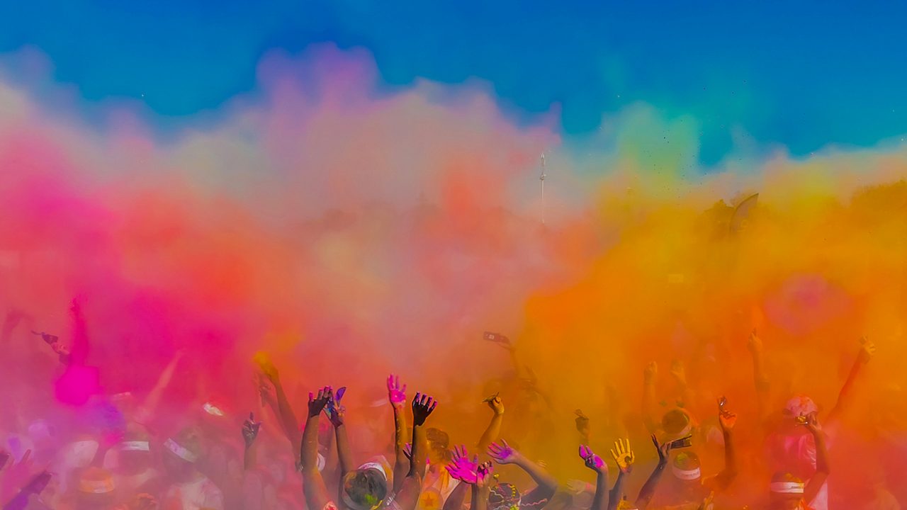 Crowd throwing bright coloured powder paint in the air, Holi Festival Dahan