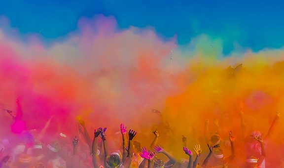 Crowd throwing bright coloured powder paint in the air, Holi Festival Dahan