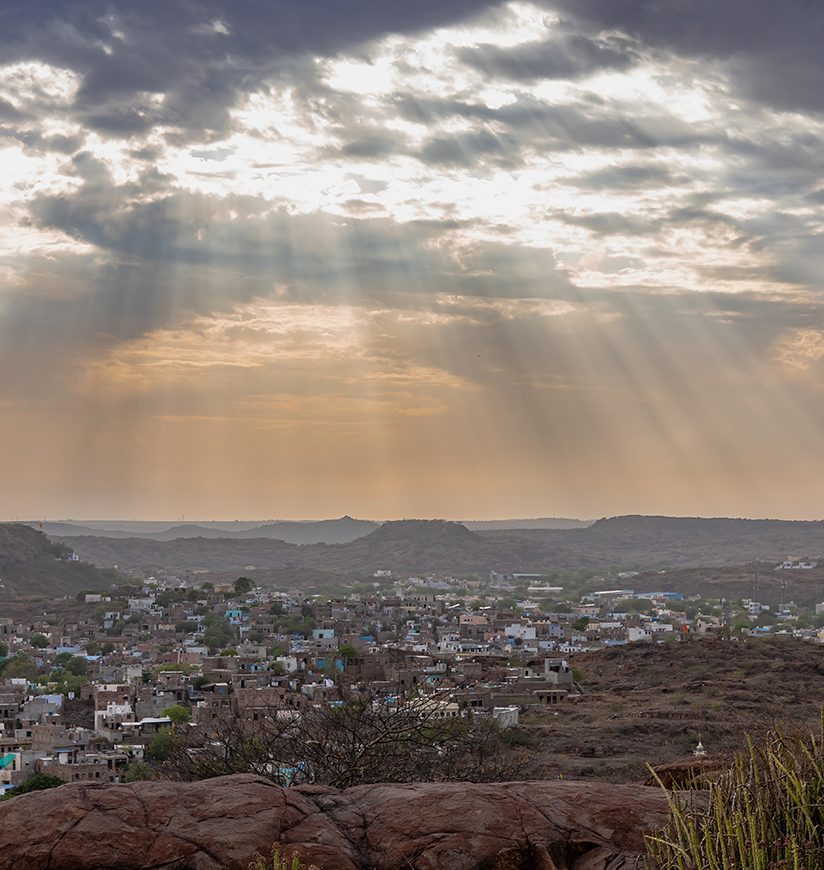 city view with dramatic sun beams orange sky at evening from mountain top