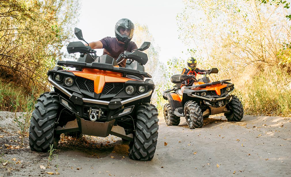 Two quad bike riders travels in forest, front view