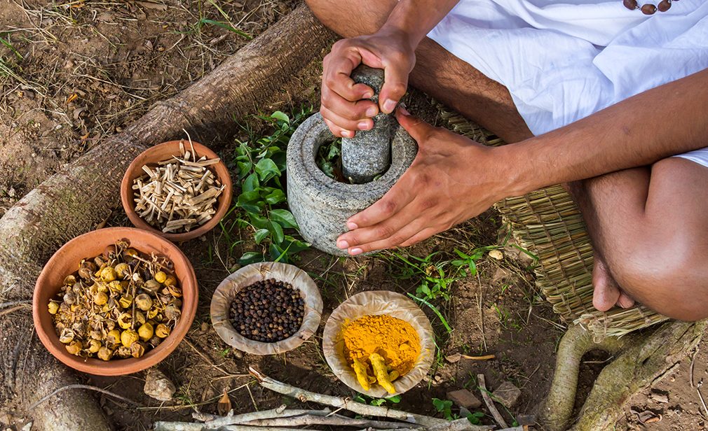 A young man preparing ayurvedic medicine in the traditional manner.