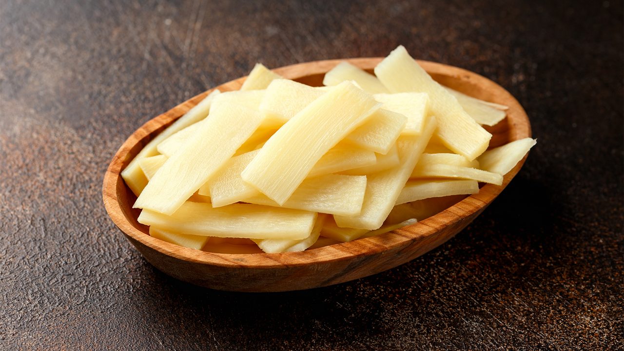 Sliced canned bamboo shoots in wooden bowl.
