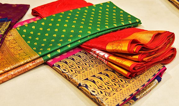 Closeup of Banares silk saris in a textile shop, displayed in front of customers. These exquisite, expensive sarees are famous for their gold and silver zari, brocade. Incredible India.