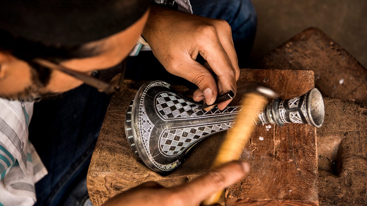 Bidar, Karnataka, India/ December 8, 2018: A Bidri craftsman engraves a traditional design on a vase, its grooves which will then be filled with fine silver wire.