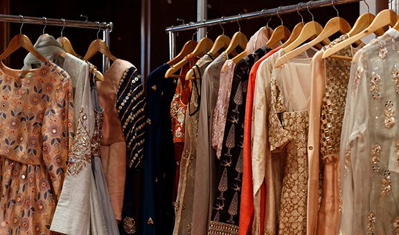 A Modern Happy smiling Young attractive Indian Asian woman or female professional fashion stylist standing in a designer boutique store and looking at the camera. self-employment and startup concept.