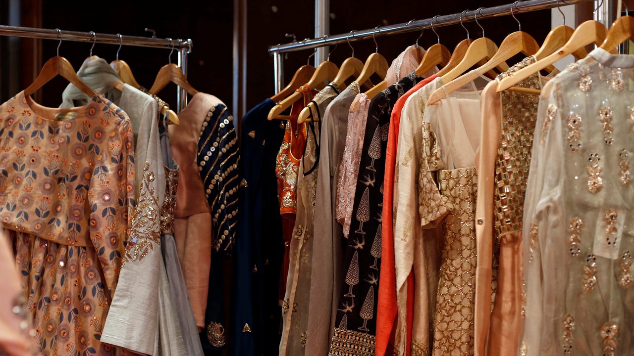 A Modern Happy smiling Young attractive Indian Asian woman or female professional fashion stylist standing in a designer boutique store and looking at the camera. self-employment and startup concept.