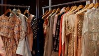 A Modern Happy smiling Young attractive Indian Asian woman or female professional fashion stylist standing in a designer boutique store and looking at the camera. self-employment and startup concept.