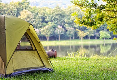 Camping green tent in forest near lake