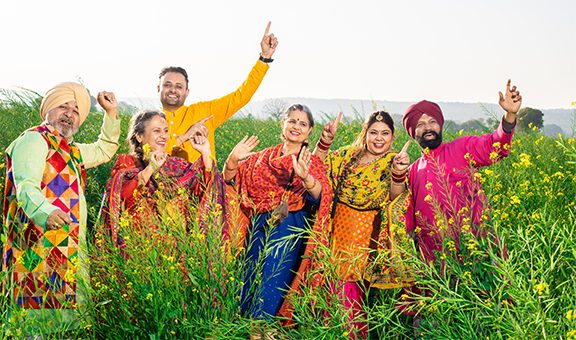 Punjabi sikh family doing bhangra dance in agriculture field celebrating Baisakhi or vaisakhi festival.