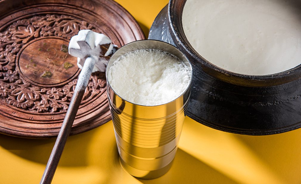 Indian sweet Lassi made up of milk, curd, sugar and salt mixed with ice cubes, served in a jumbo steel glass, prepared in traditional earthen pot 