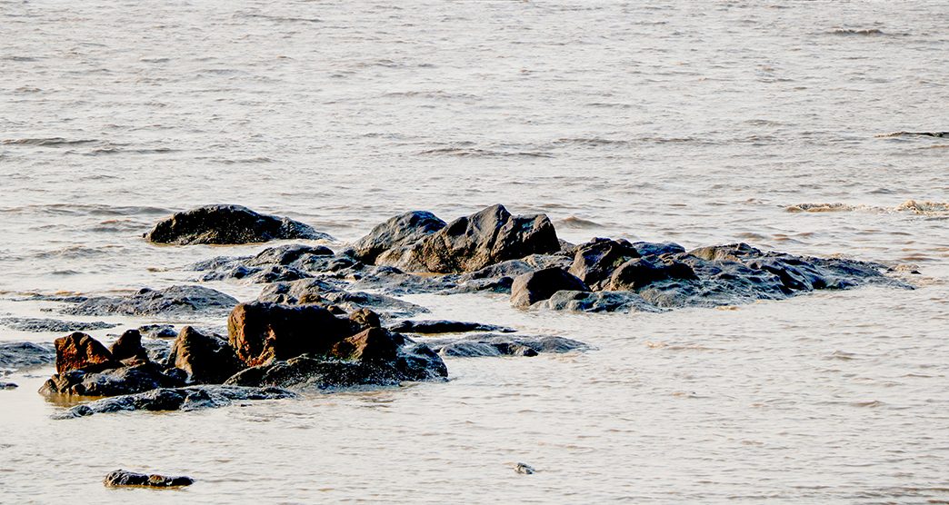 big rock in water at beach of devka beach-daman-india