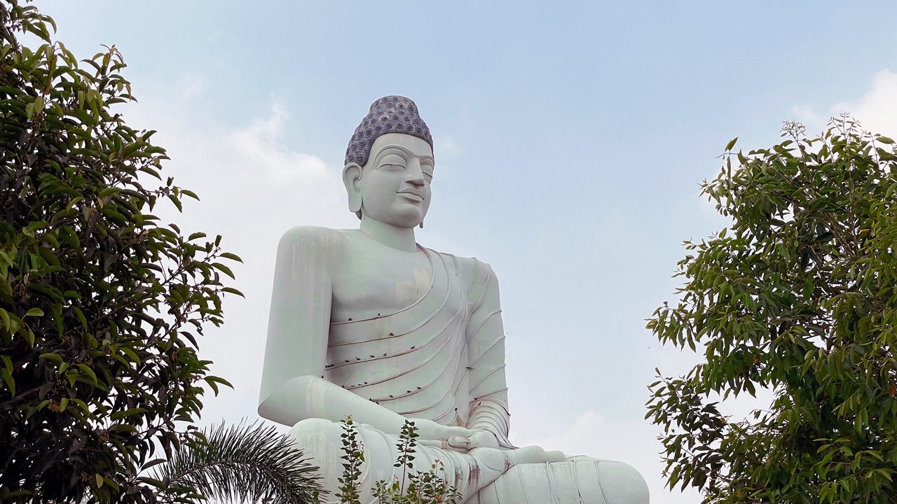 Lord Buddha in Meditation with clear blue sky and green trees at Amaravati