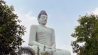 Lord Buddha in Meditation with clear blue sky and green trees at Amaravati