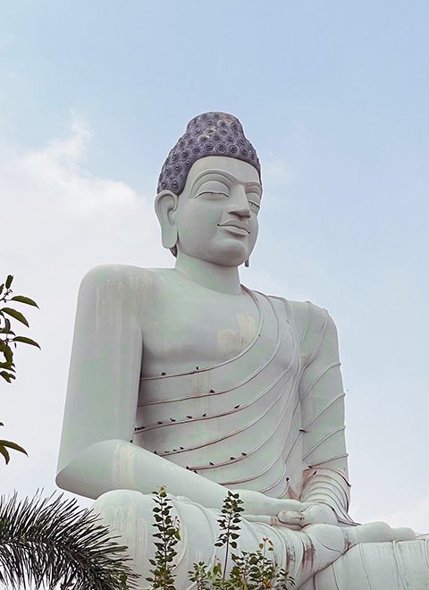 Lord Buddha in Meditation with clear blue sky and green trees at Amaravati