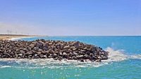 Landscape of Dwarka coastline Gujarat India with clean waters, beach and windmill turbines to generate environment friendly power for the local infrastructure. Blue skies reflect of the Arabian Sea