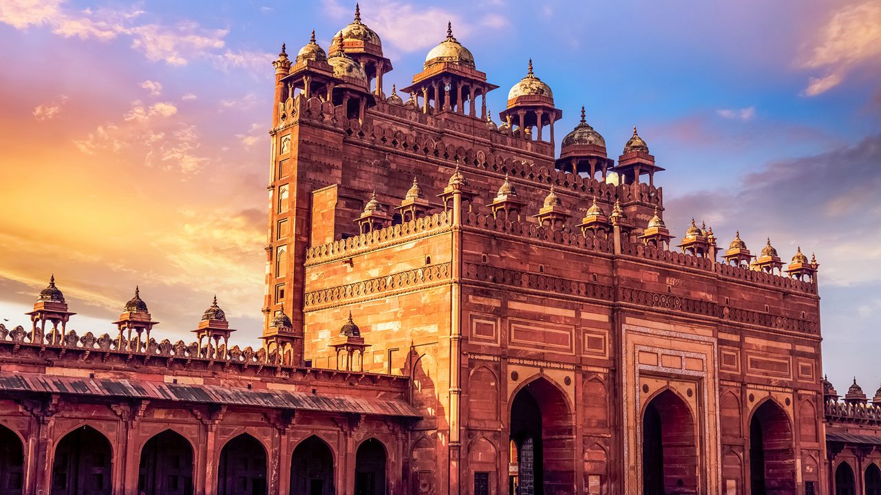 Medieval red sandstone gateway known as the Buland Darwaza at Fatehpur Sikri Agra at sunset with moody sky.