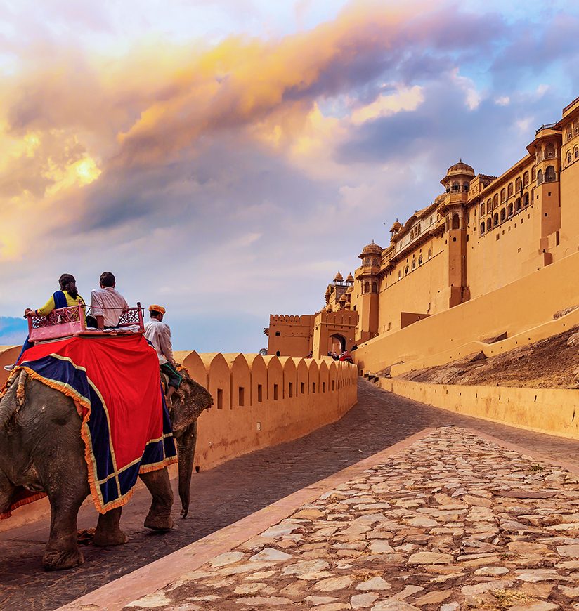 Tourists enjoy an elephant ride at Amer Fort Jaipur Rajasthan at sunset.