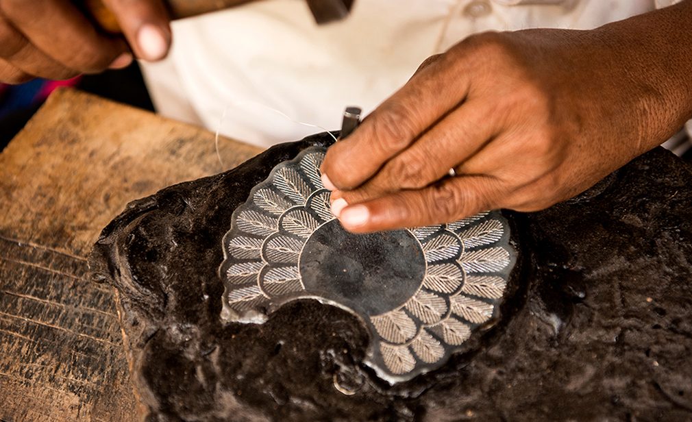 Bidar, Karnataka, India/ December 10, 2018: A Bidri craftsman inlays fine silver wire in to the grooves of a peacock tail, in Bidar, Karnataka, India.