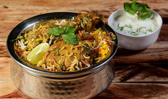 Traditional Hyderabadi Chicken dum Biryani made of Basmati rice cooked with masala spices, served with Onion raita, selective focus