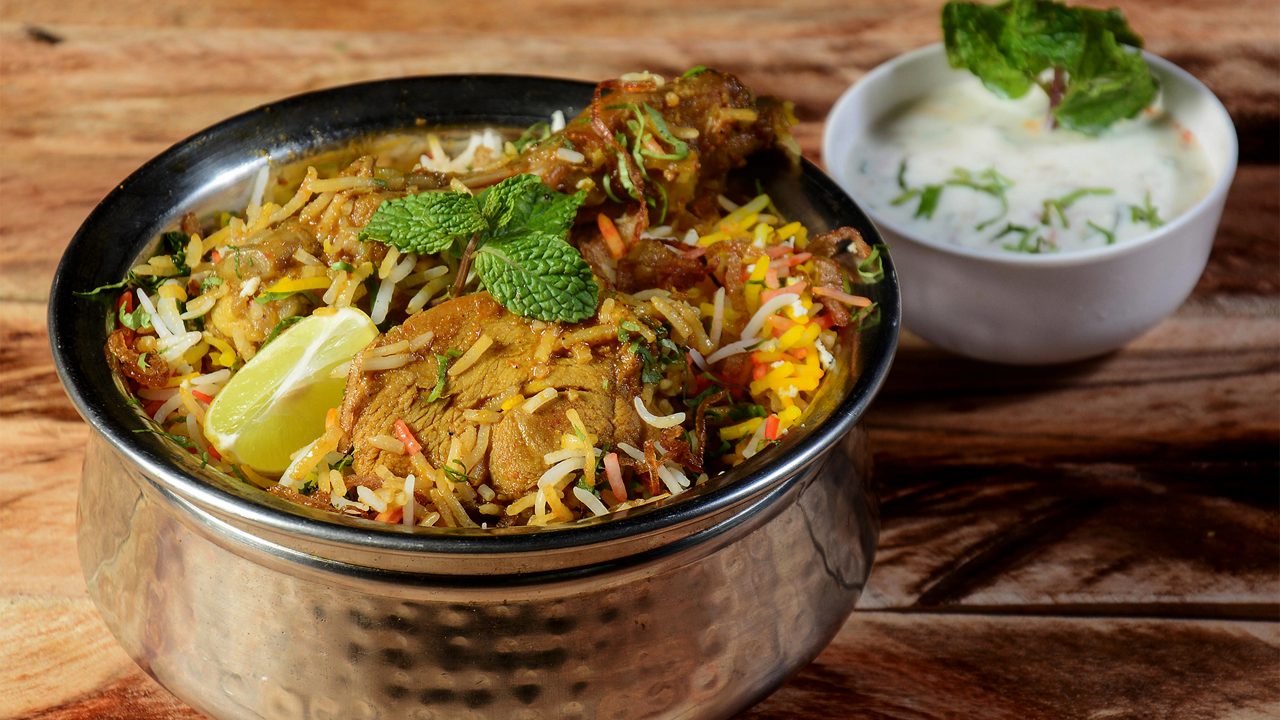Traditional Hyderabadi Chicken dum Biryani made of Basmati rice cooked with masala spices, served with Onion raita, selective focus
