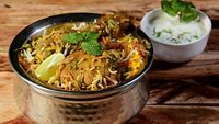 Traditional Hyderabadi Chicken dum Biryani made of Basmati rice cooked with masala spices, served with Onion raita, selective focus