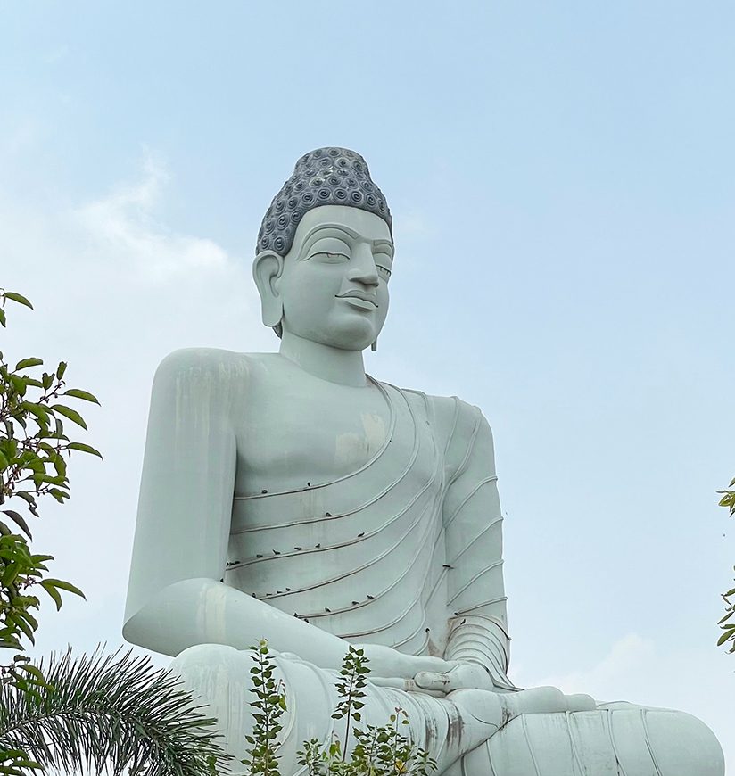 Lord Buddha in Meditation with clear blue sky and green trees at Amaravati