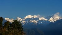 Beautiful panoramic view on snow-capped Kangchenjunga mountain in Himalaya range with trees in foreground, seen from Pelling, Sikkim, India