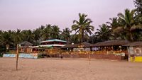 02/19/2019  Gokarna , India Indian people (youth) playing voleyball on sand   of   Kudle beach in South India . Line of cafeson background