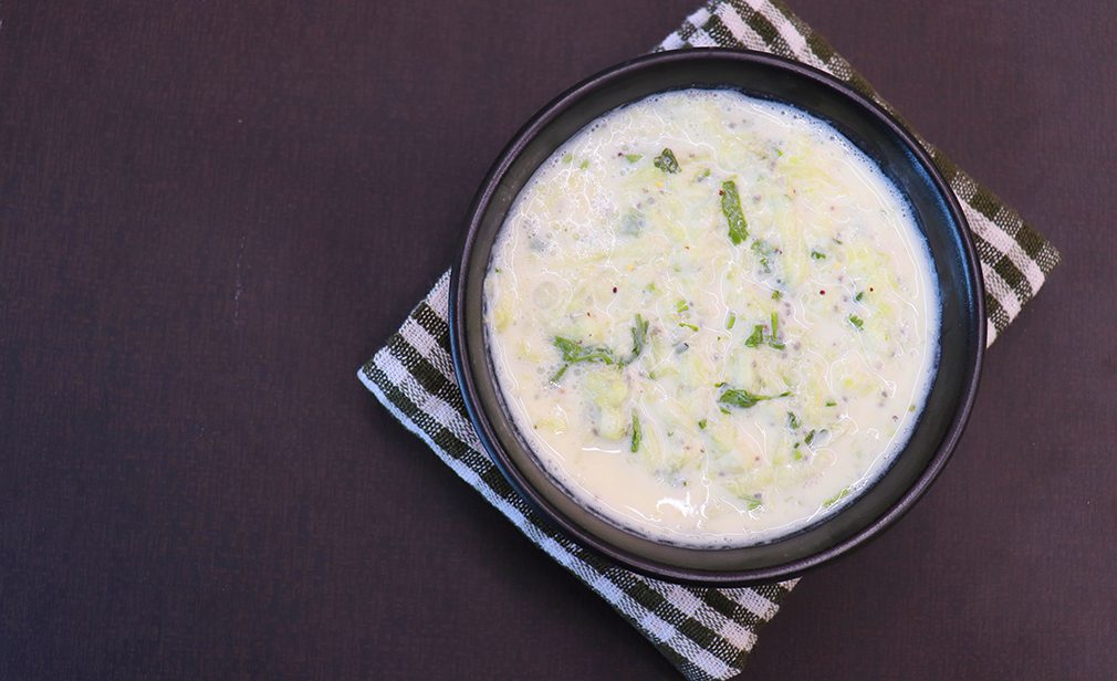 Indian Fresh sauce called Raita with herbs, curd and grated cucumber close-up in a bowl on the table. with some saute vegetables like green bell papers and fresh green peas