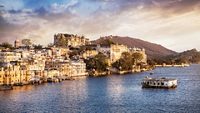 Lake Pichola with City Palace view at cloudy sunset sky in Udaipur, Rajasthan, India