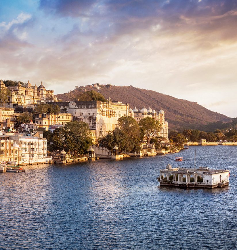 Lake Pichola with City Palace view at cloudy sunset sky in Udaipur, Rajasthan, India