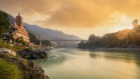 Stunning view of the Ganga river embankment with the Lakshman Jhula bridge and Tera Manzil Temple (Trimbakeshwar) during a beautiful sunset. Rishikesh, Uttarakhand, India.