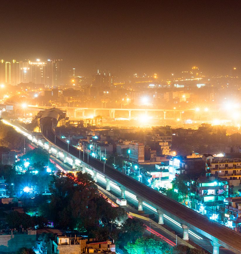 aerial view of the cityscape of Noida gurgoan delhi at night  with the elevated metro track and metro station visible. The city residences and offices are also clearly visible