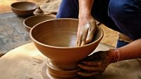 Pottery - skilled wet hands of potter shaping the clay on potter wheel. Pot, vase throwing. Manufacturing traditional handicraft Indian bowl, jar, pot, jug. Shilpagram, Udaipur, Rajasthan, India