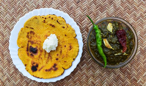 Indian popular dish makki di roti and Sarson da saag, mustard leaves curry and unleavened maize flour bread served in an authentic way with white butter and green chilly.Punjabi traditional style food