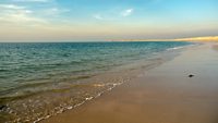 Shivrajpur beach near dwarka gujarat india at dusk with bue arabian sea and the waves of the ocean. The expansive landscape and the clouds on the blue sky over the deserted beach show how untouched