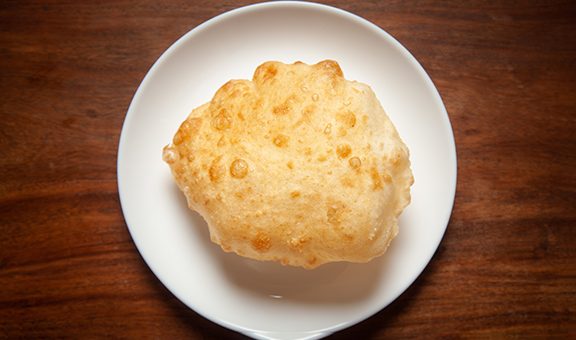 Close-up of deep fried bhature (maida puri) made from  all purpose flour, served hot in white ceramic plate.