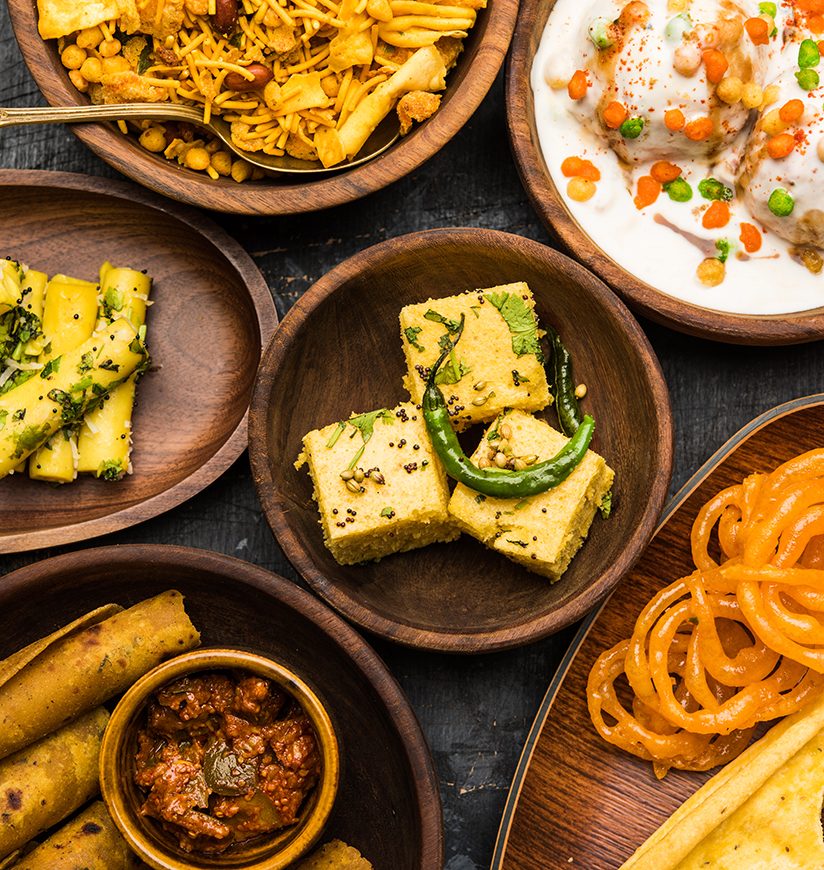 Group of Gujarati snacks like jalebi-fafda, thepla, khaman dhokla, aloo bhujiya, khandvi,khakra, dahi vada, gathiya with hot tea