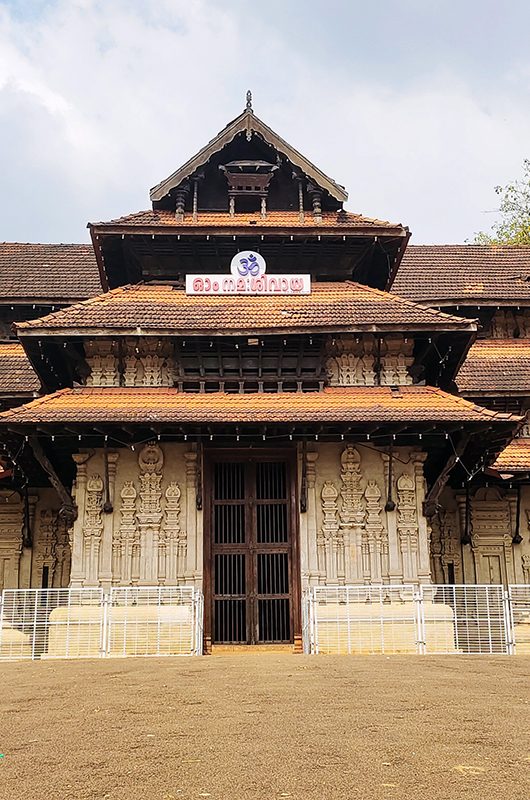 Vadakkumnathan or lord shiva ancient old traditional style south indian hindu religion stone temple building in kerala, thrissur. Front view with Om Namah Shivaya Mantra text in Malayalam language.