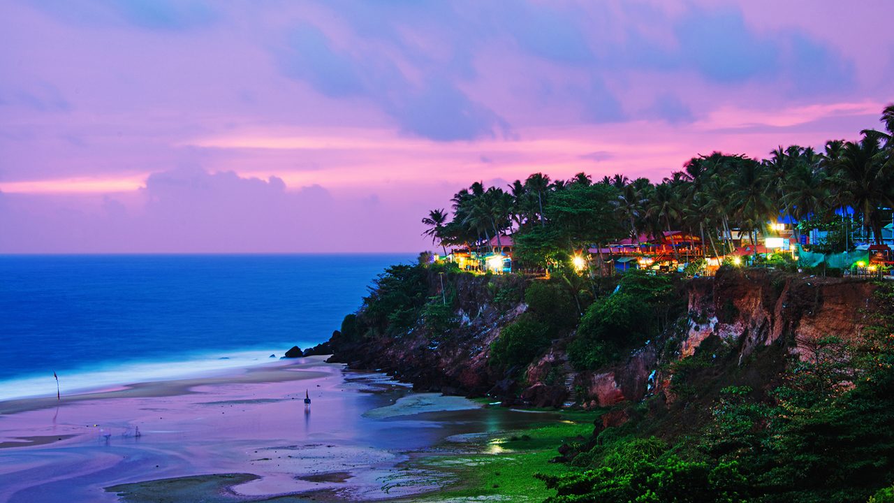 Kerala, India. Varkala beach at night, various cafes and restaurants at the cliff with colorful sunset sky and motion blurred Laccadive Sea and Papanasam beach in Kerala, India